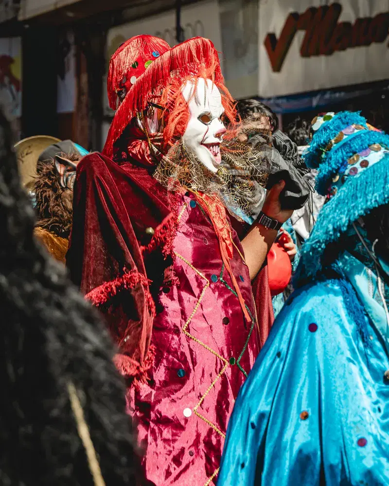 Comparsa con trajes turquesa y rojo en un desfile de disfraces